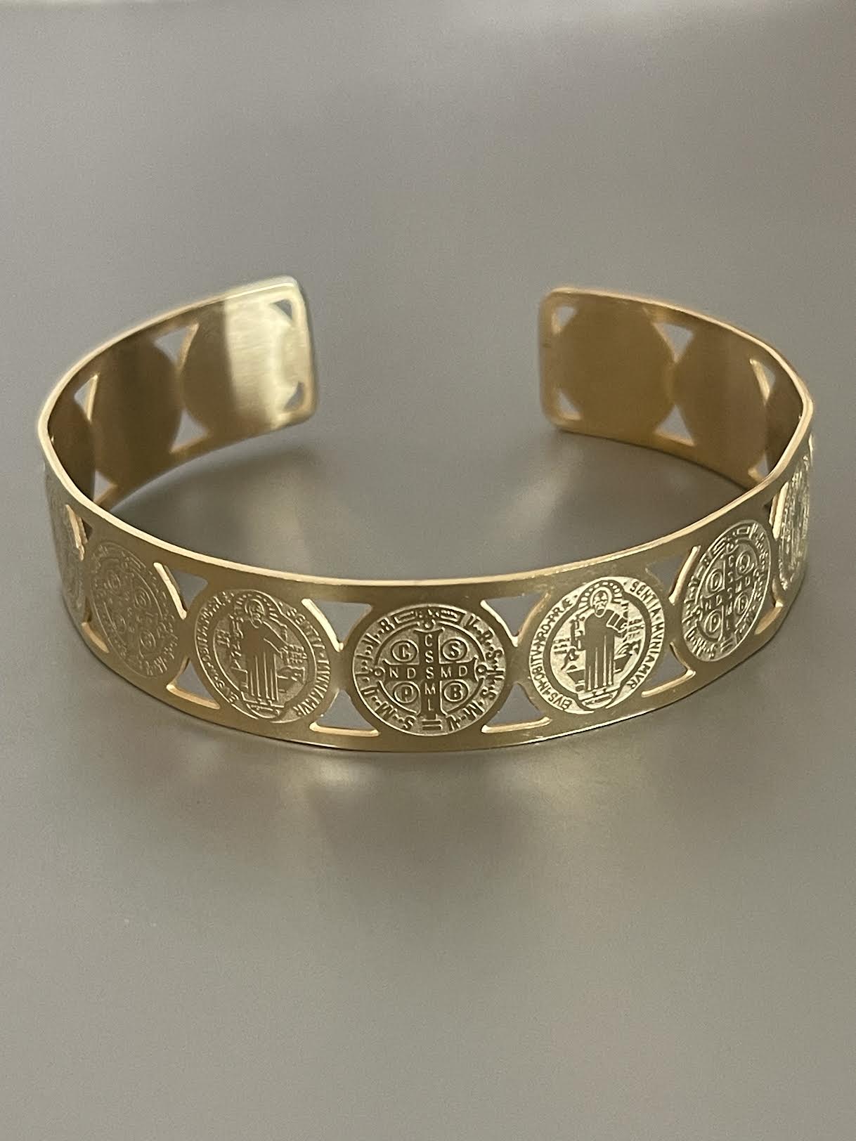Pulsera Hippie Chic religiosa de acero inoxidable dorado con lindas imagenes de San Benito y cruz. Diametro 6.5 c.