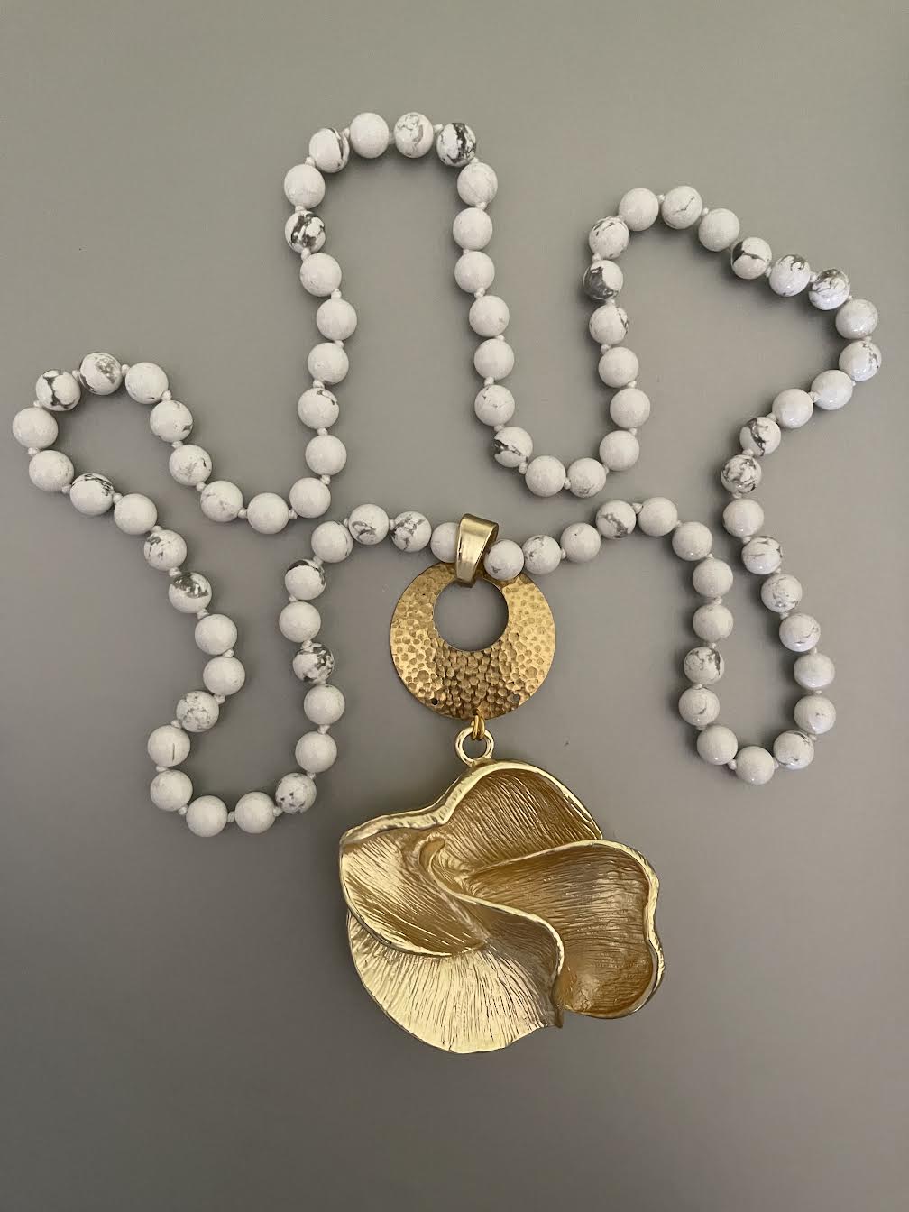 Collar Hippie Chic largo con preciosa flor dorado opaco y piedras naturales blancas anudadas con leves vetas grises.