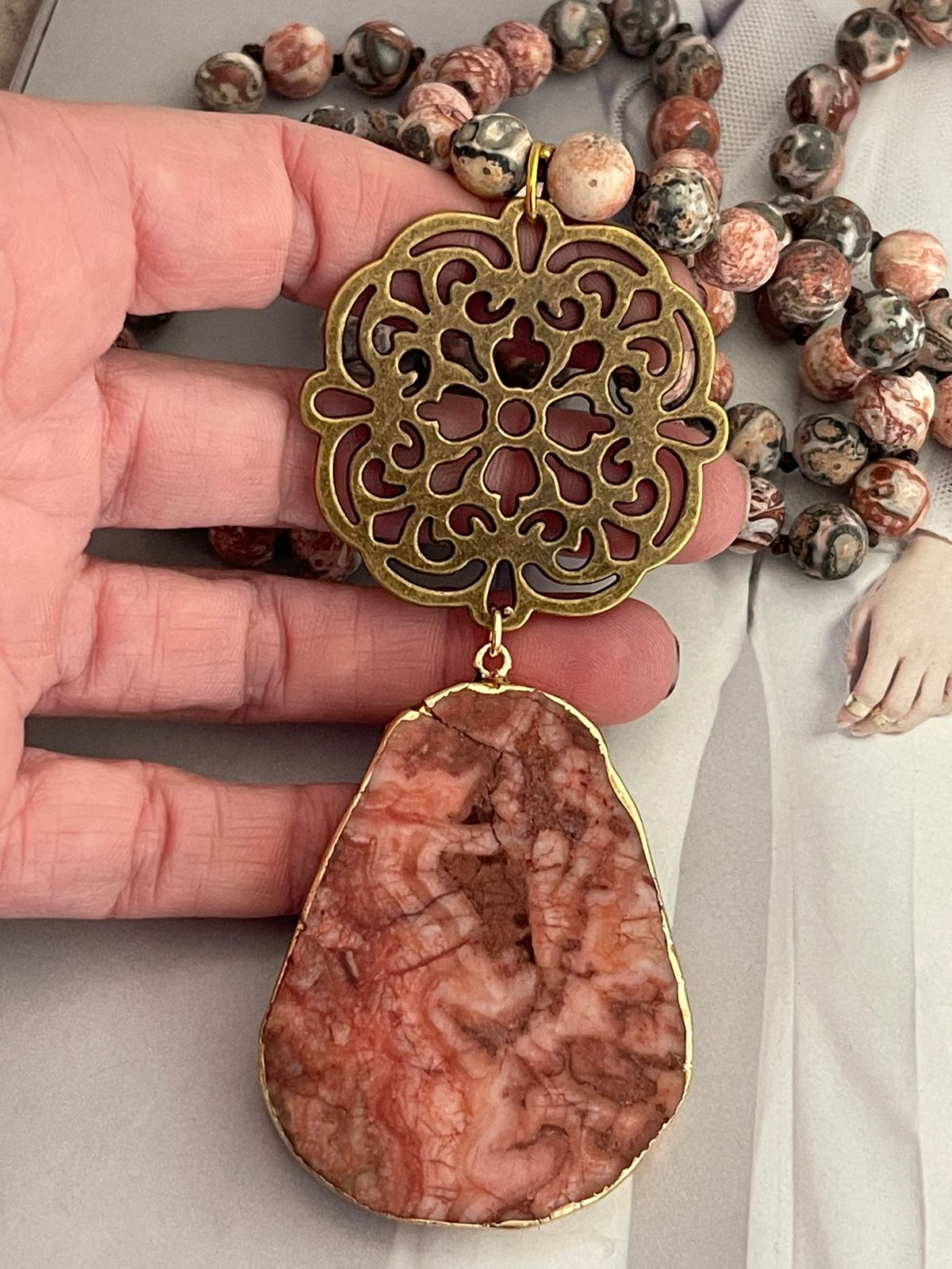 Collar Hippie Chic largo de piedras naturales anudadas en tonos rojos, rosas, blancos y marron, con colgante en los tonos y mandala y precioso mandala envejecido.