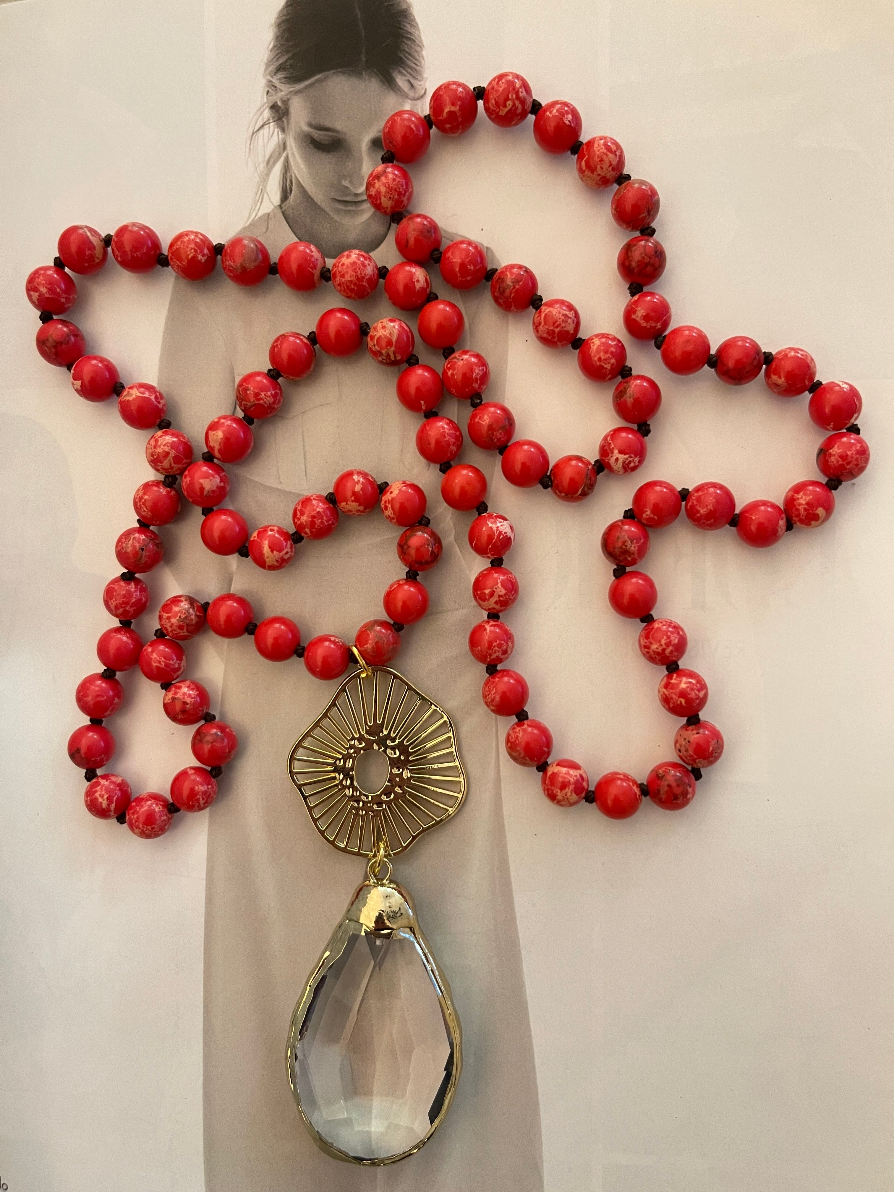 Collar Hippie Chic largo de alegres piedras anudadas en tonos rojos y colgante de cristal facetado con borde dorado.
