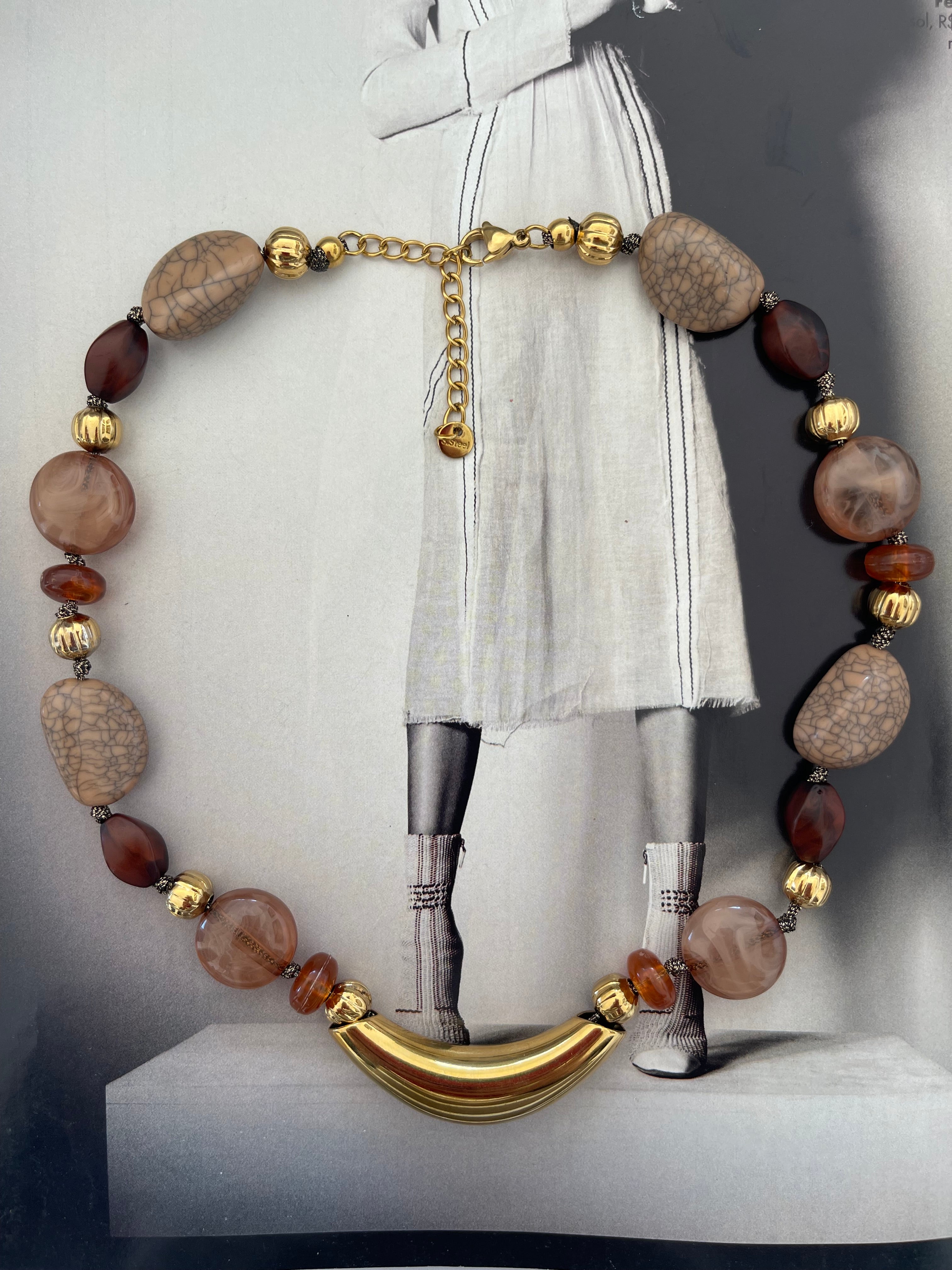 Collar Hippie Chic corto con base de acero inoxidable dorado y detalles en acrilico en tonos baige, marron y caramelo.