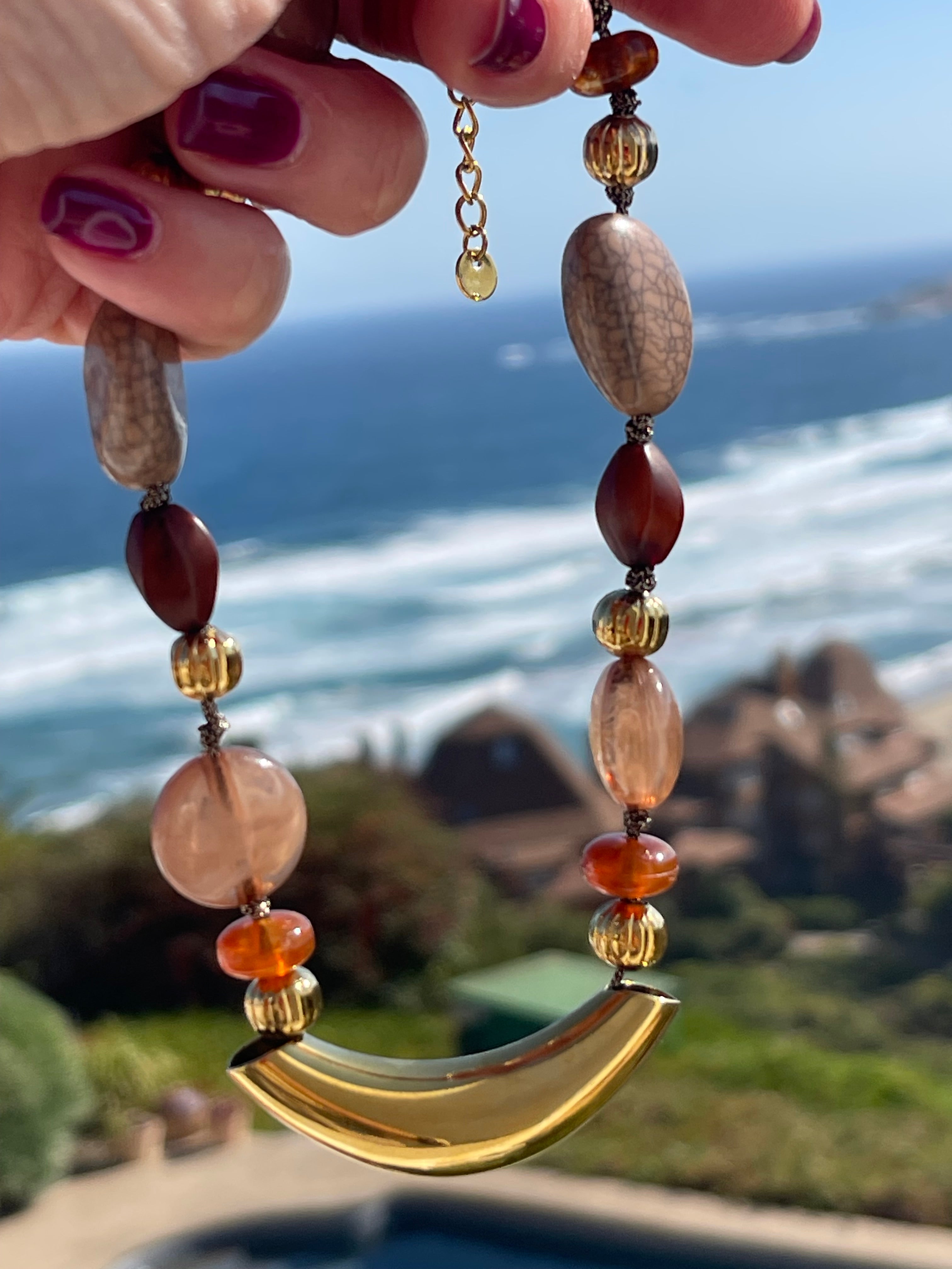 Collar Hippie Chic corto con base de acero inoxidable dorado y detalles en acrilico en tonos baige, marron y caramelo.