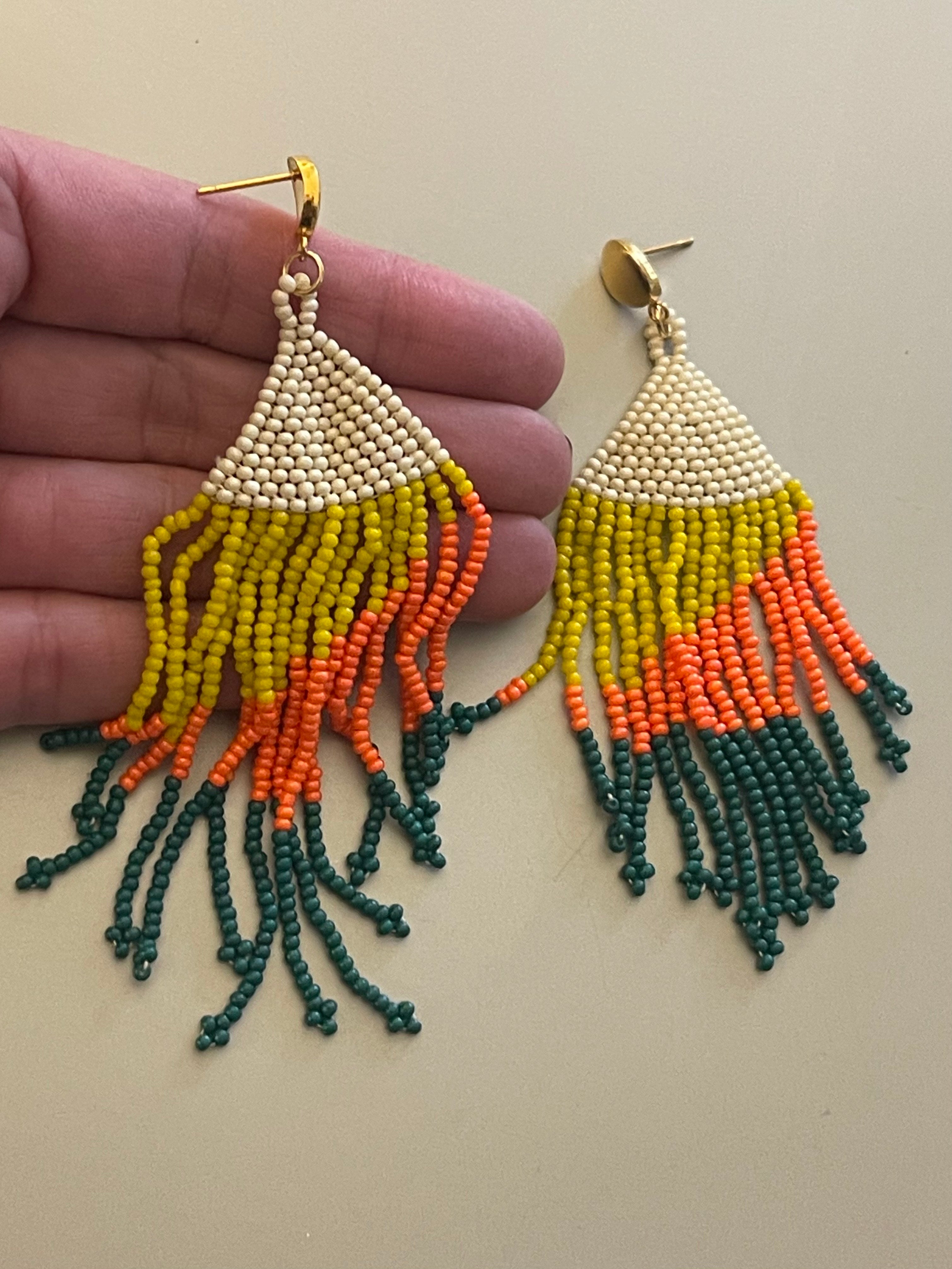 Aros Hippie Chic largos con alegres mostacillas en tonos blanco invierno, amarillo, naranjo, verde y base de acero inoxidable dorado. Largo 9 cm.