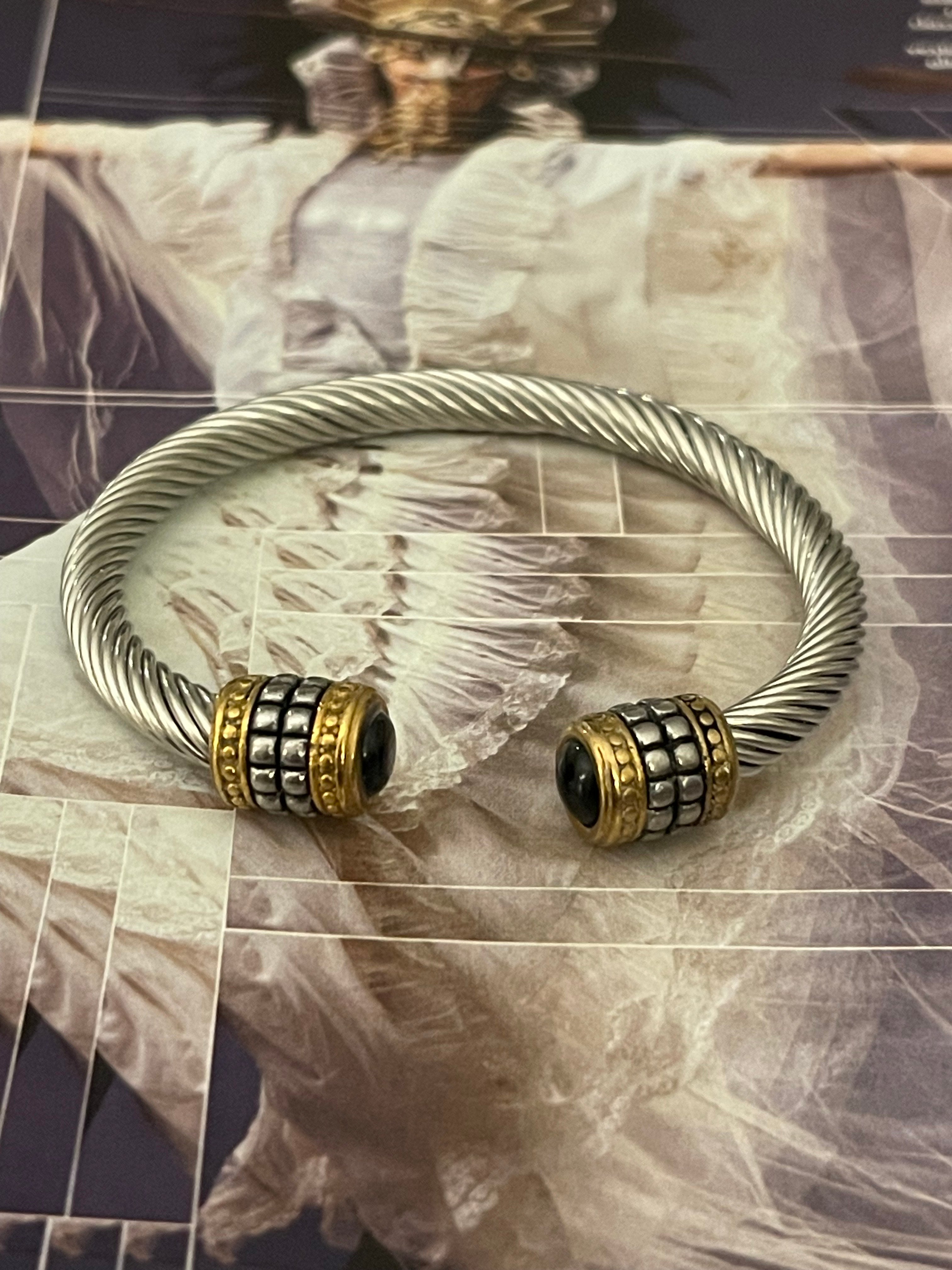 Pulsera Hippie Chic de acero inoxidable plateado y preciosos detalles en las puntas en acero dorado y cristal negro.