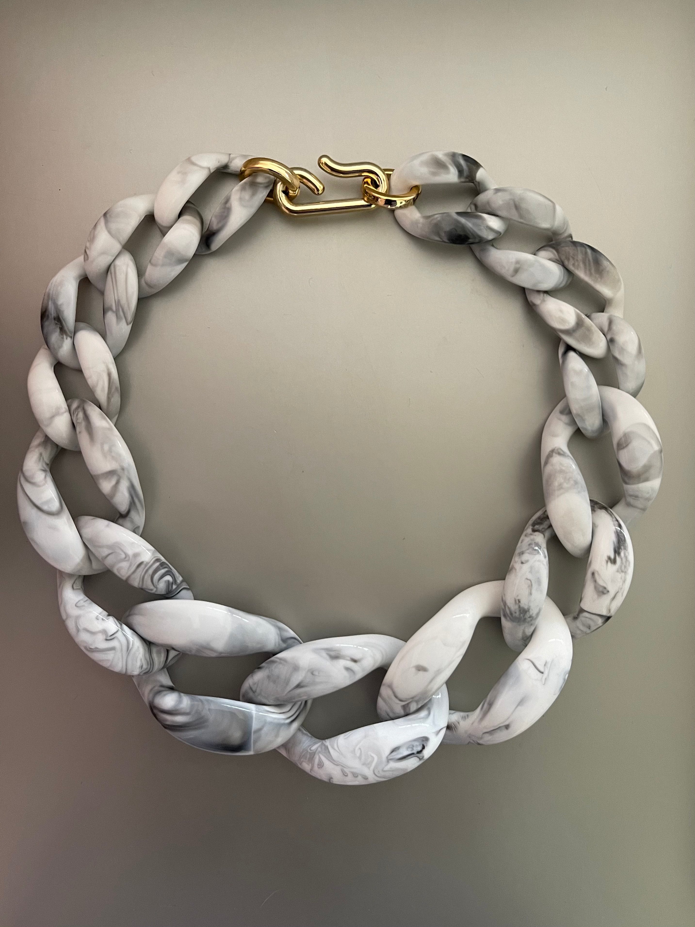 Collar Hippie Chic corto de acrilico en elegantes tonos blancos, vetas grises y broche dorado.