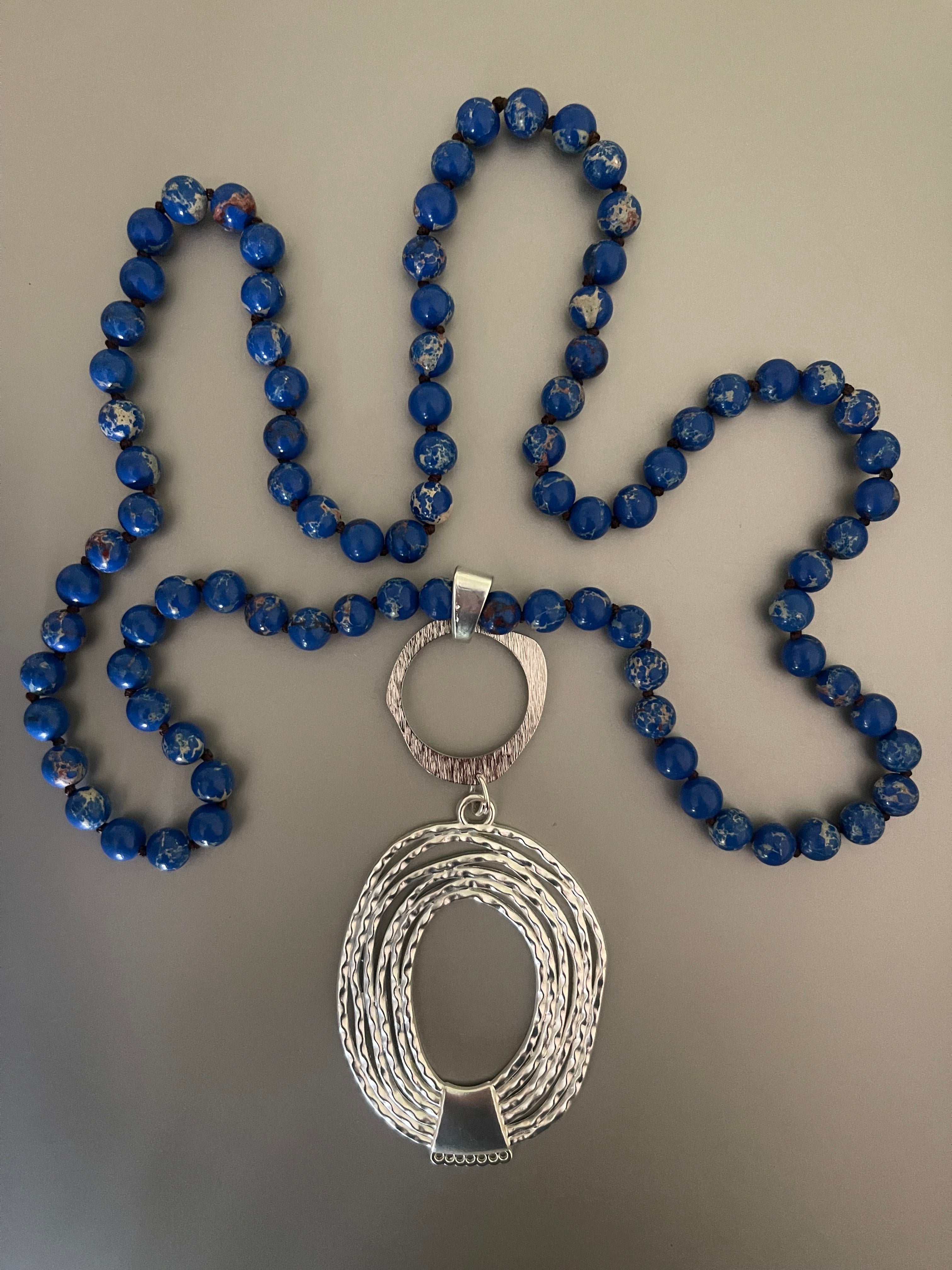 Collar Hippie Chic largo con predcioso colgante pltaedo y alegres piedras naturales anudadas en tonos azulinos con leves vetas blancas.