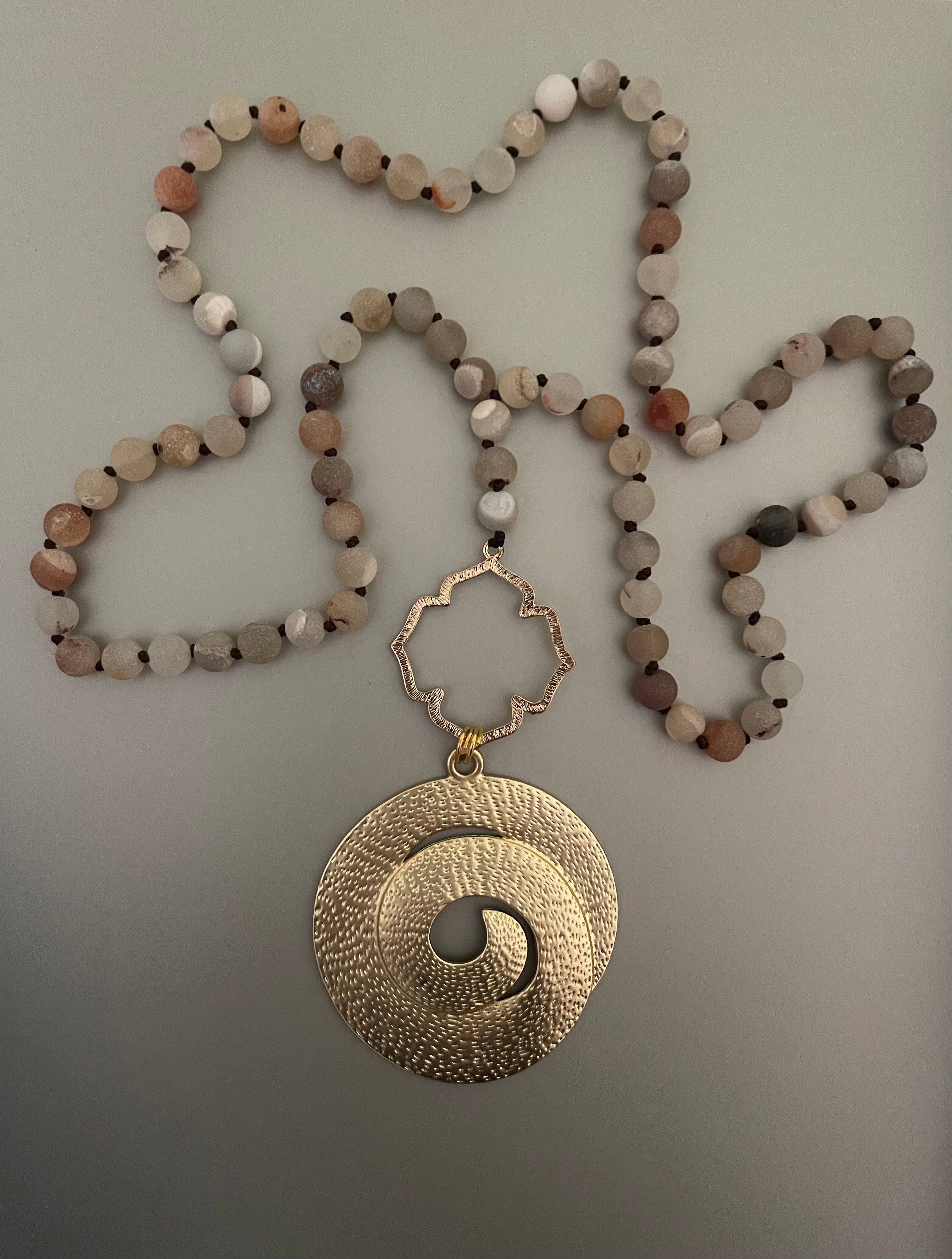 Collar Hippie Chic largo con elegante colgante dorado y piedras naturales rodinadas y anudadas en tonos pastel.