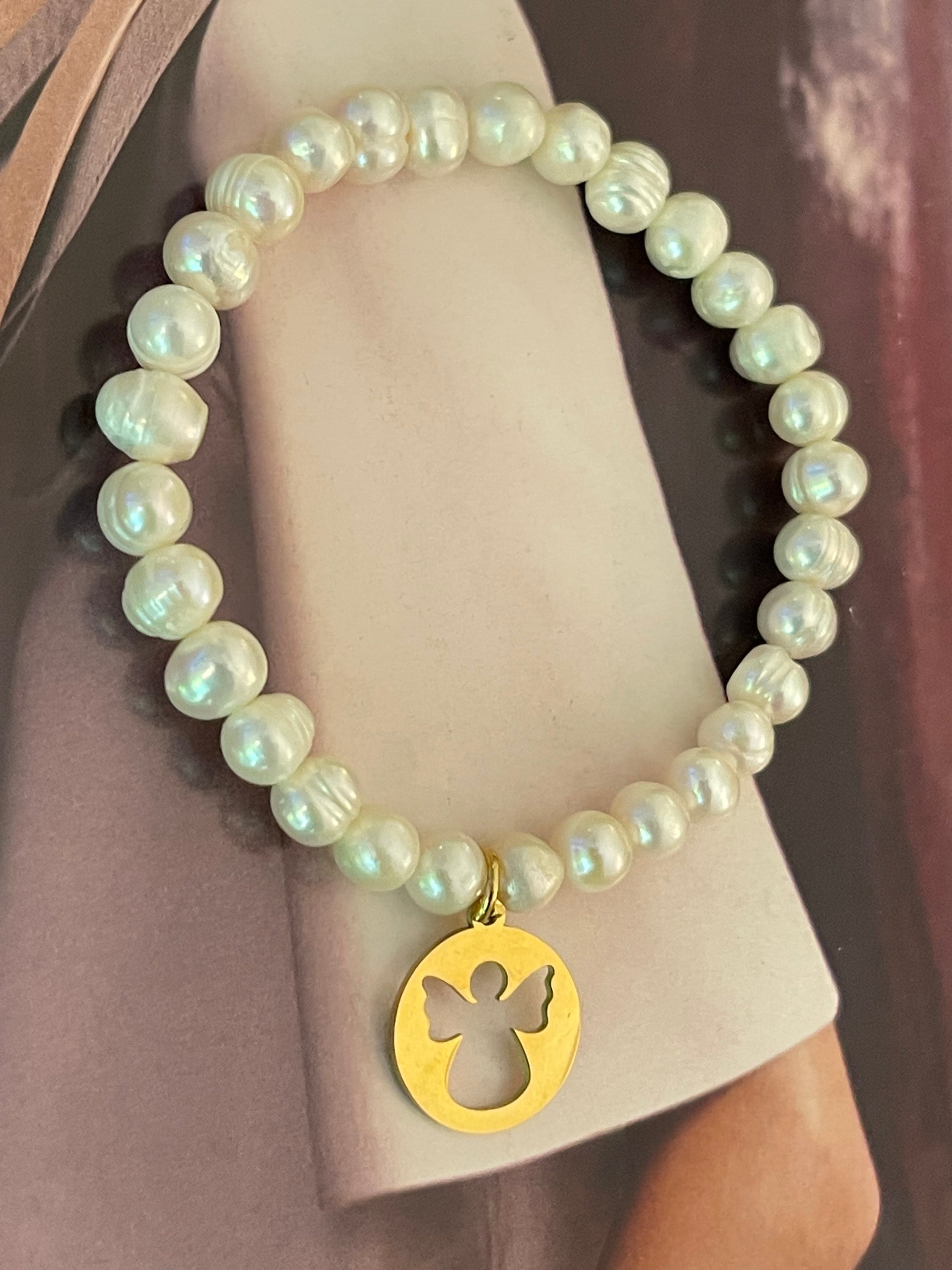Pulsera Hippie Chic elasticada de finas perlas naturales blancas y colgante de Angelito en acero inoxidable dorado.