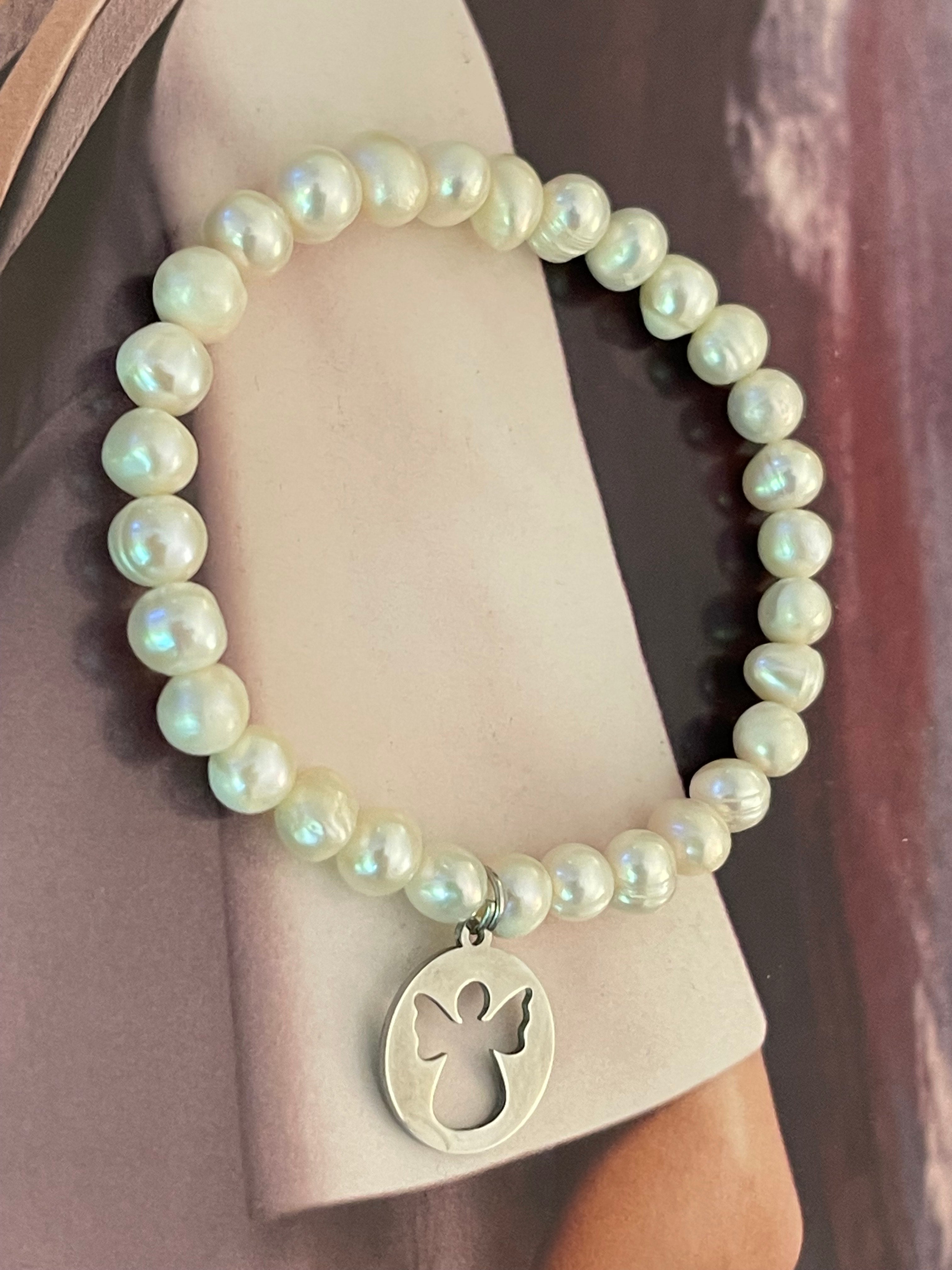 Pulsera Hippie Chic elasticada de elegantes perlas naturales blancas y colgante de angelito en acero inoxidable plateado.