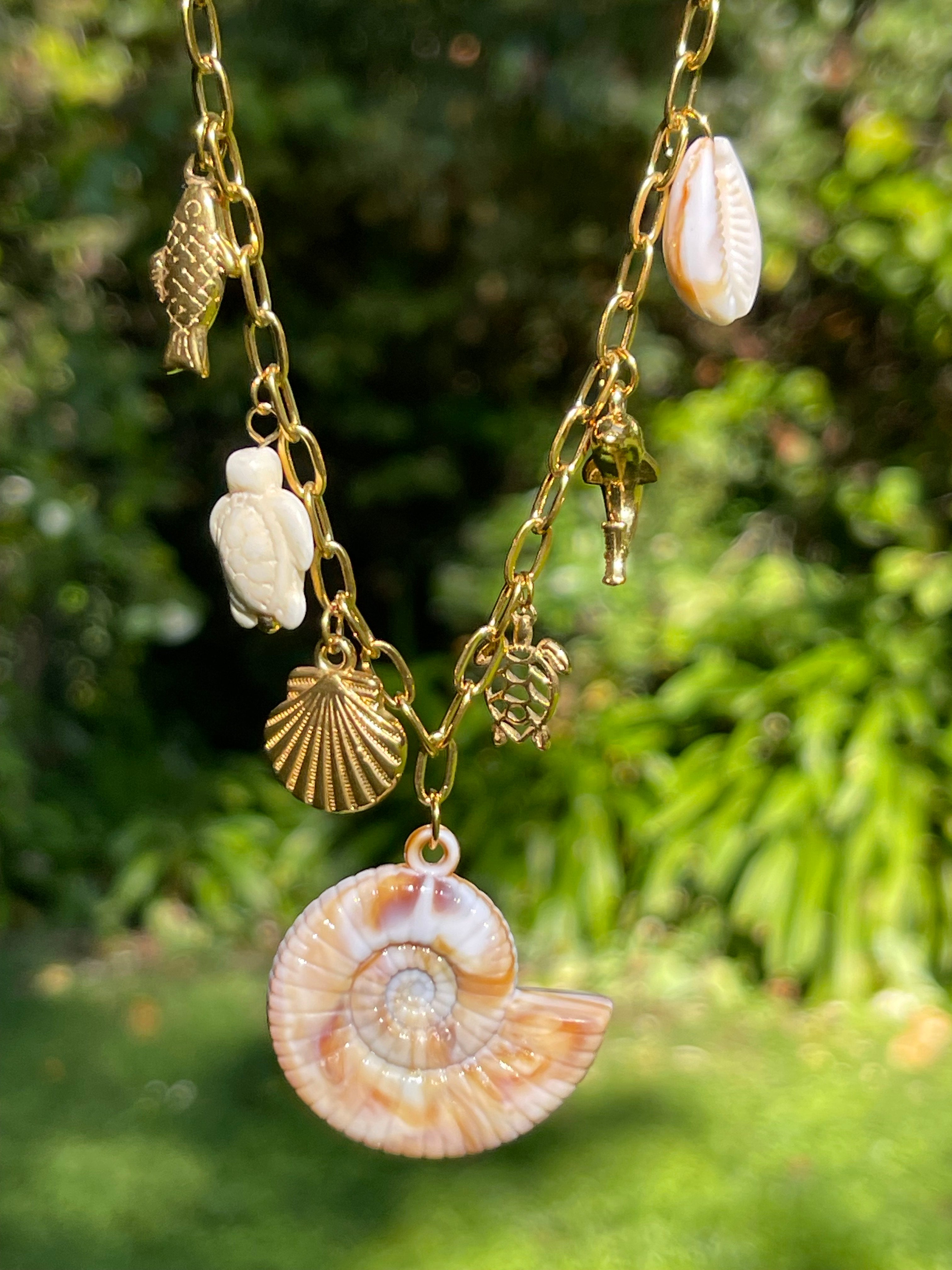 Collar Hippie Chic corto de cadena de acero inoxidable dorado y preciosos colgantes con motivos maritimos en acero y acrilico en tonos beige.