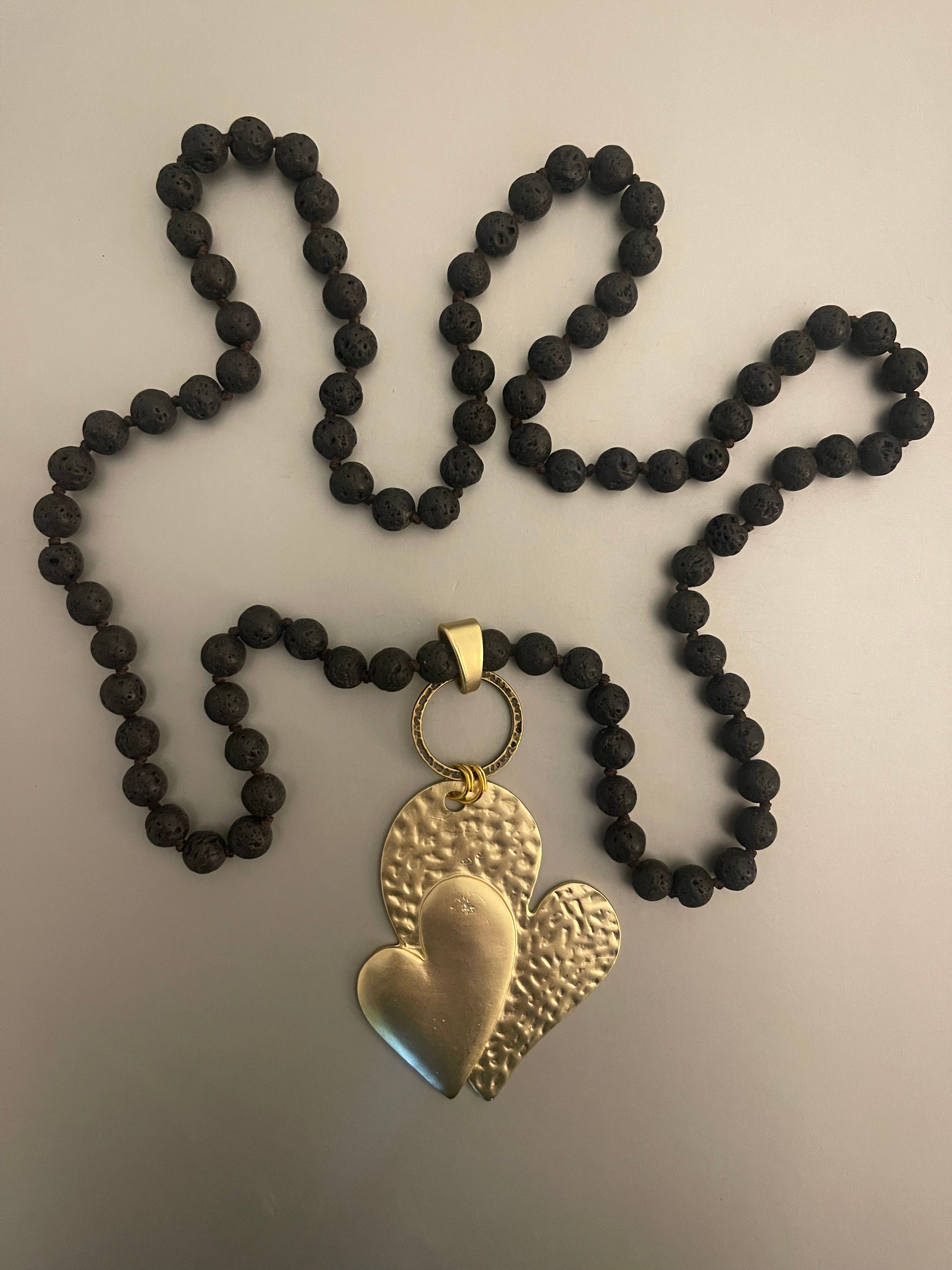 Collar Hippie Chic largo de piedras volcanicas naturales negras anudadas y precioso colgante de corazon dorado opaco.