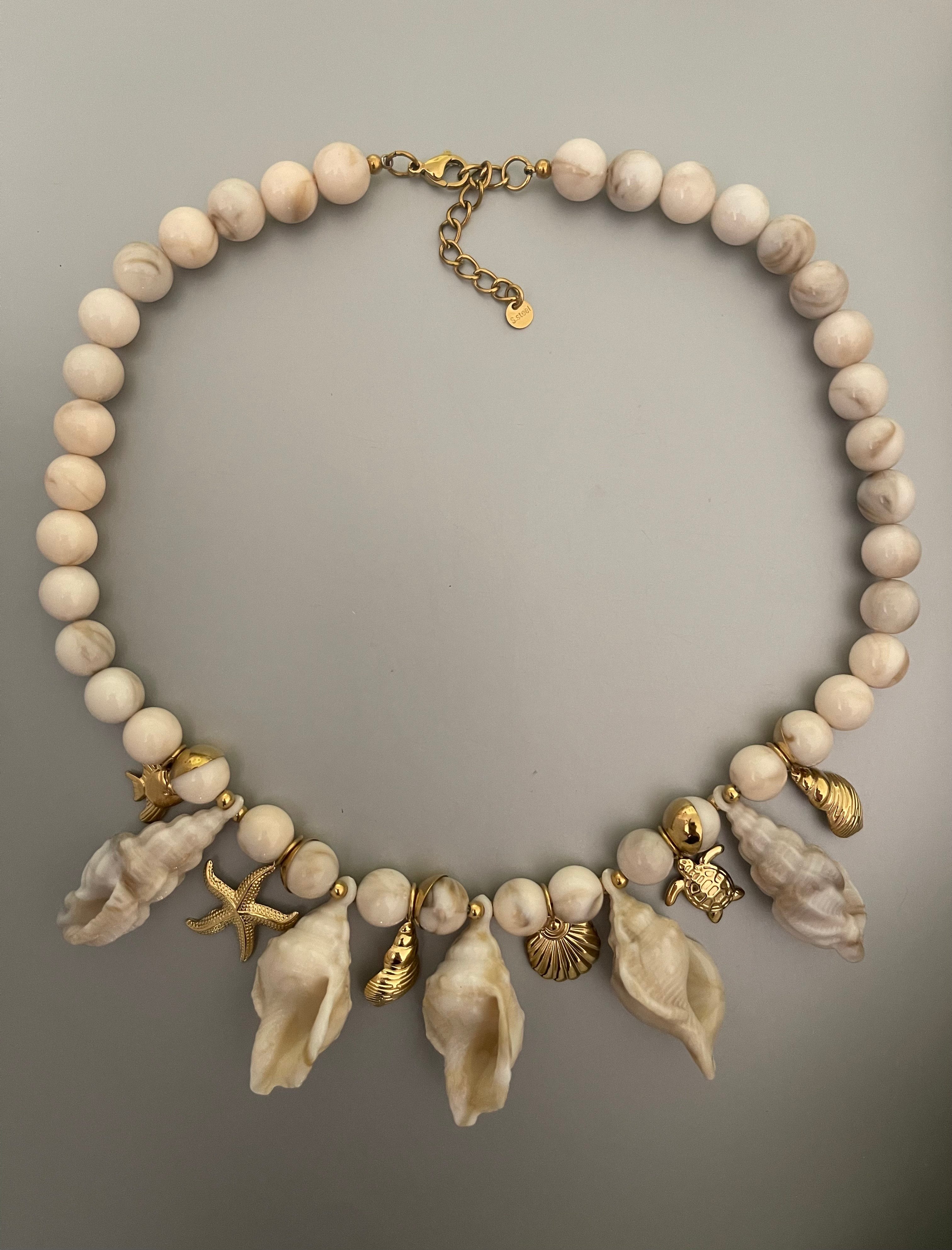 Collar Hippie Chic corto con preciosos motivos maritimos en acrilico beige y colgantes y cadena en acero inoxidable dorado.