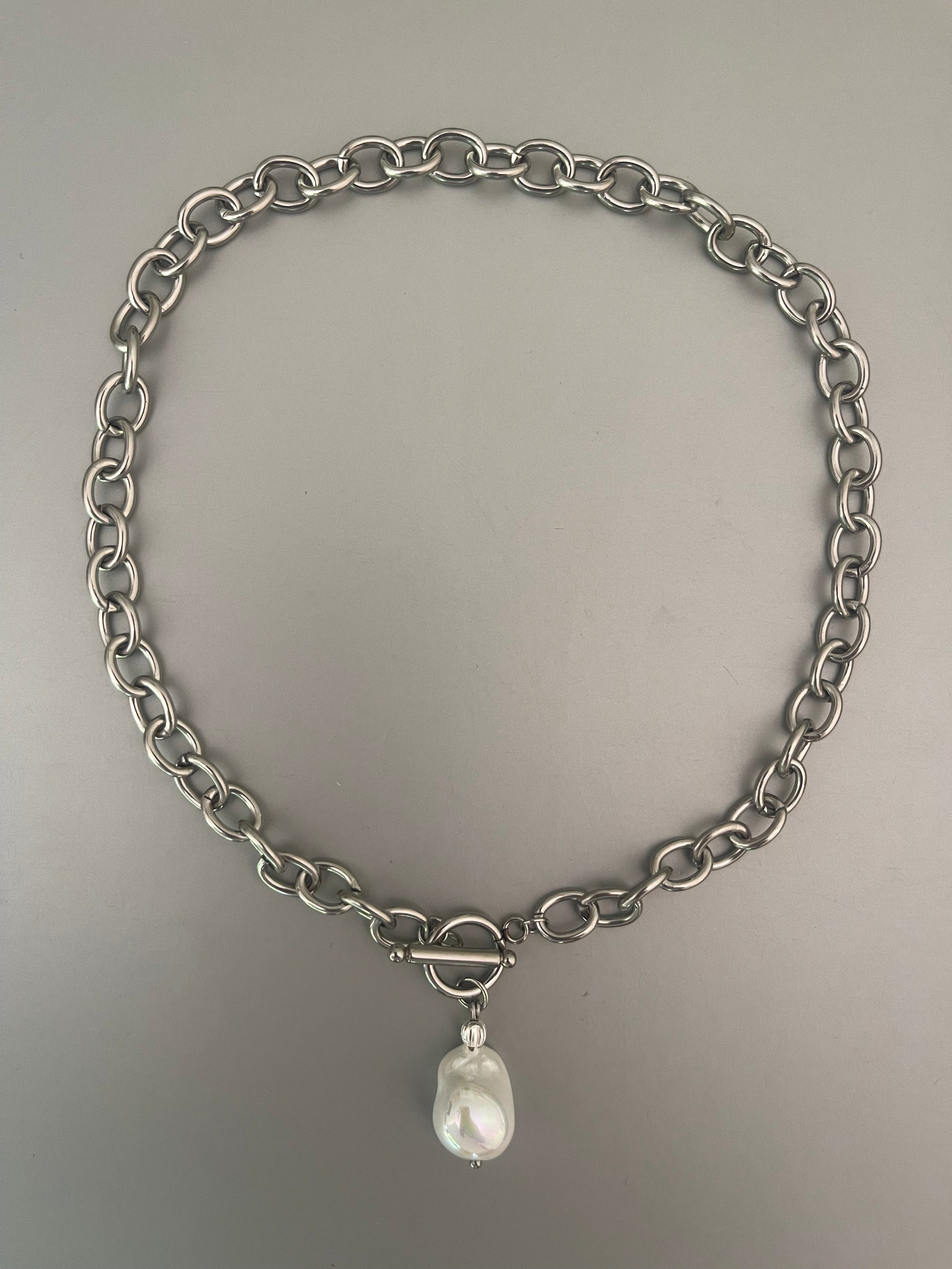 Collar Hippie Chic corto de cadena de acero inoxidable plateado con cierre OT y preciosa perla barroca blanca de fantasia con un elegante esmaltado.
