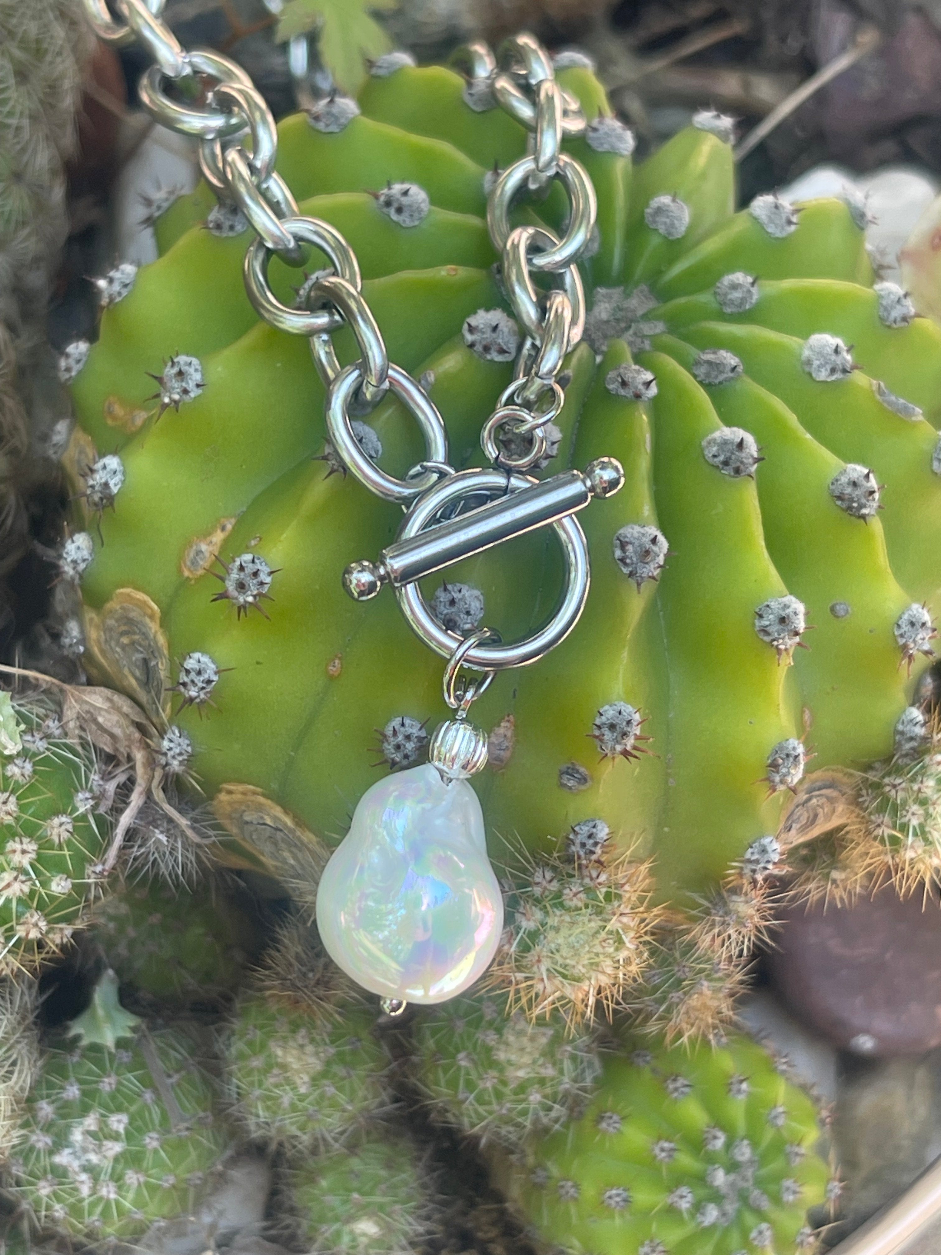 Collar Hippie Chic corto de cadena de acero inoxidable plateado con cierre OT y preciosa perla barroca blanca de fantasia con un elegante esmaltado.