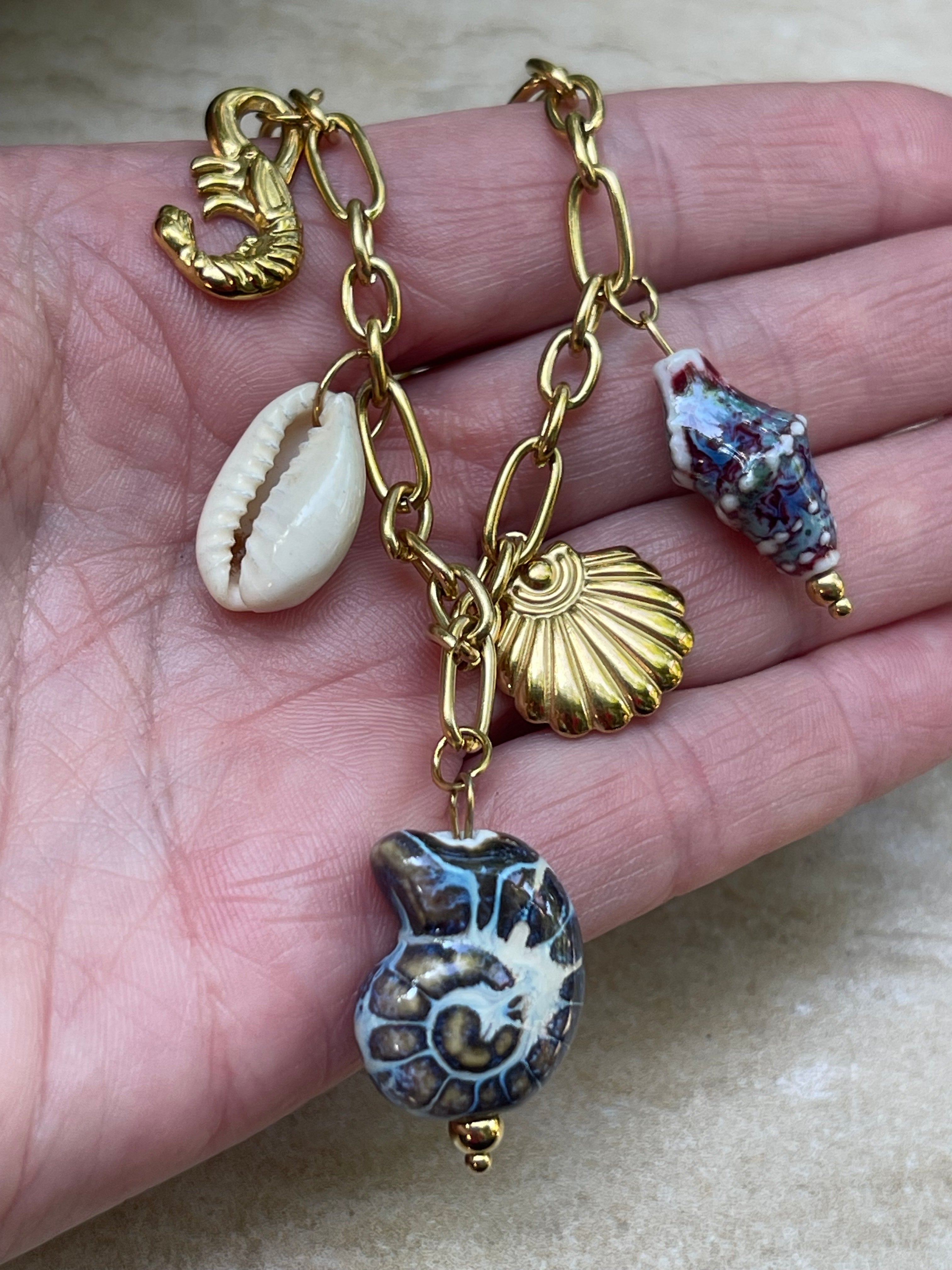 Collar Hippie Chic corto de cadena de acero inoxidable dorado y preciosos colgantes en tonos azules con motivos de mar de ceramica, acero, concha natural y perla de fantasia.