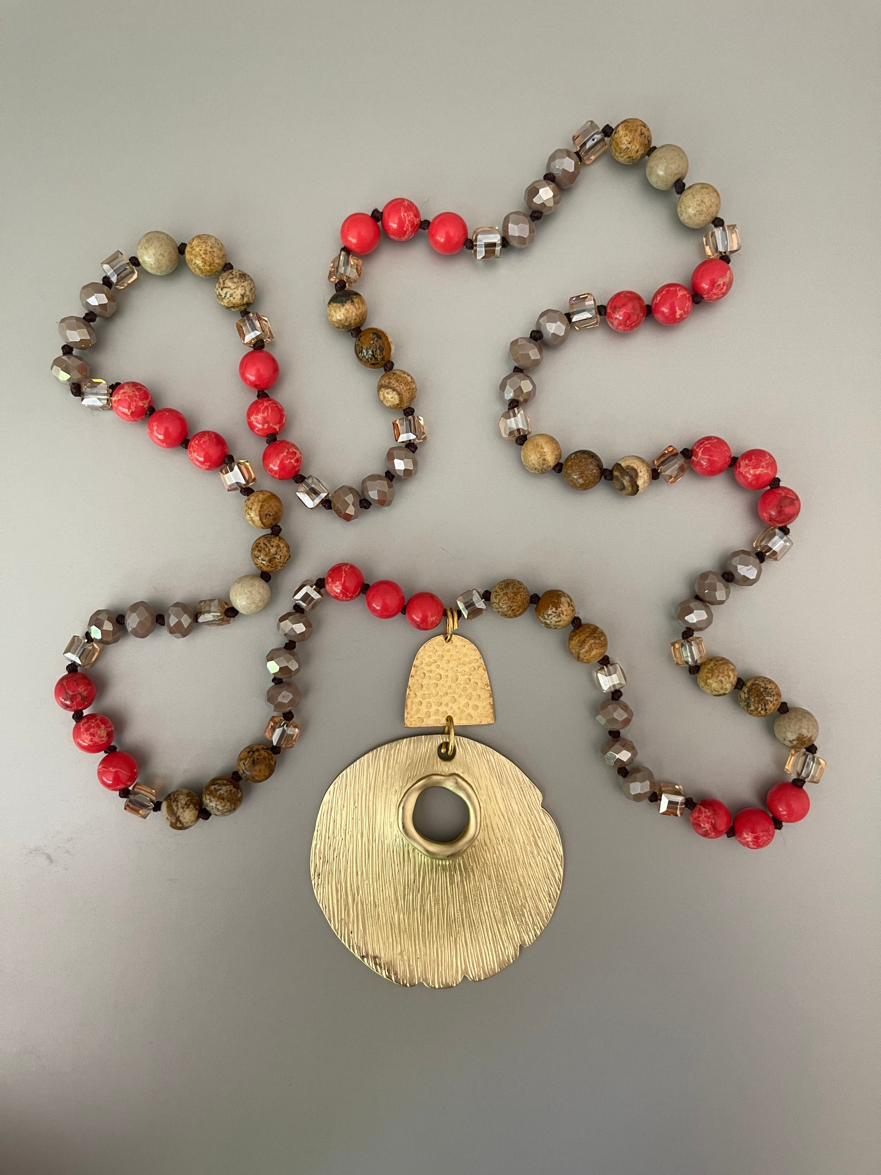 Collar Hippie Chic largo de piedras y cristales anudados en tonos naranjos y beige con elegante colgante dorado.