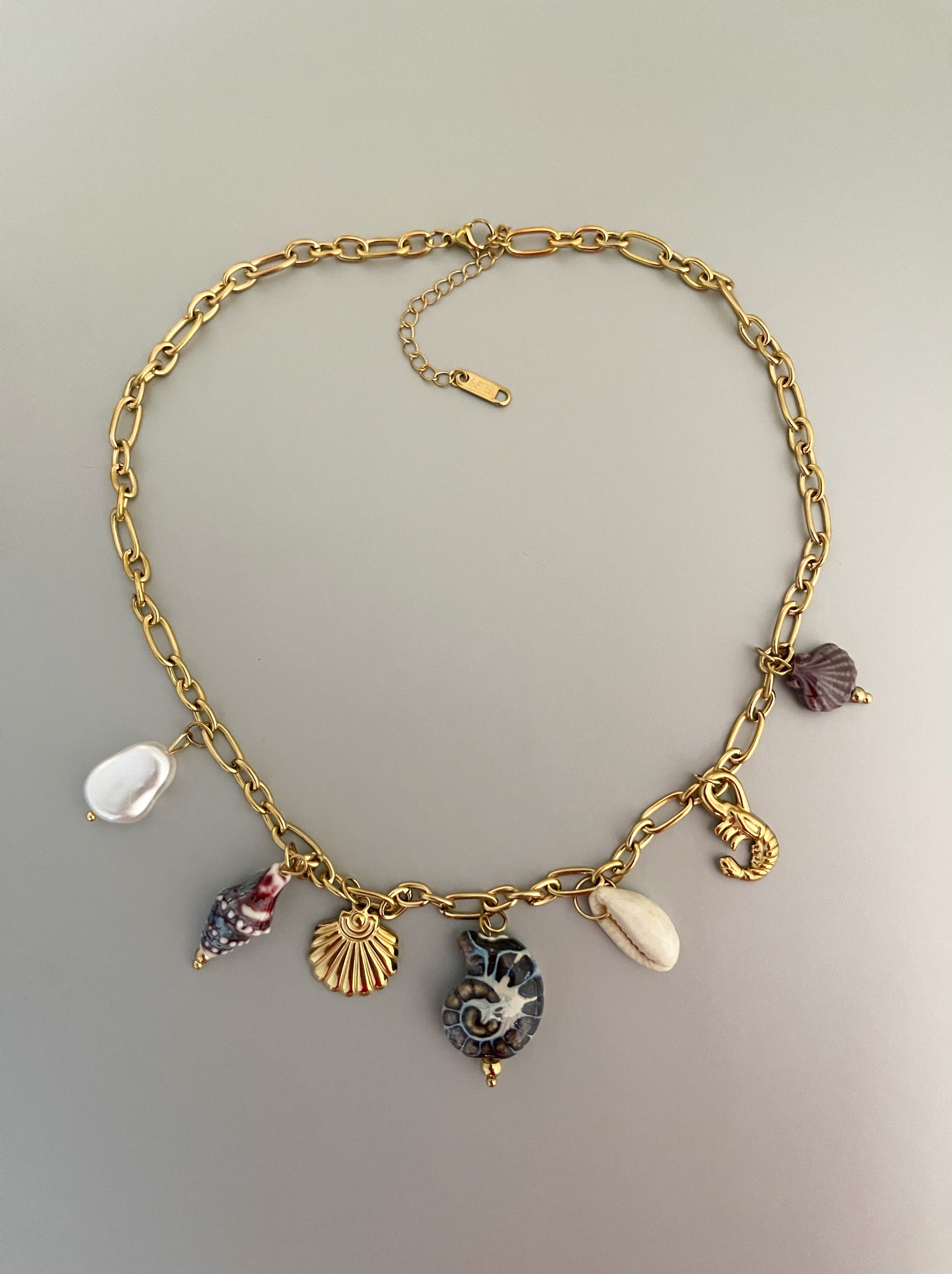 Collar Hippie Chic corto de cadena de acero inoxidable dorado y preciosos colgantes en tonos azules con motivos de mar de ceramica, acero, concha natural y perla de fantasia.