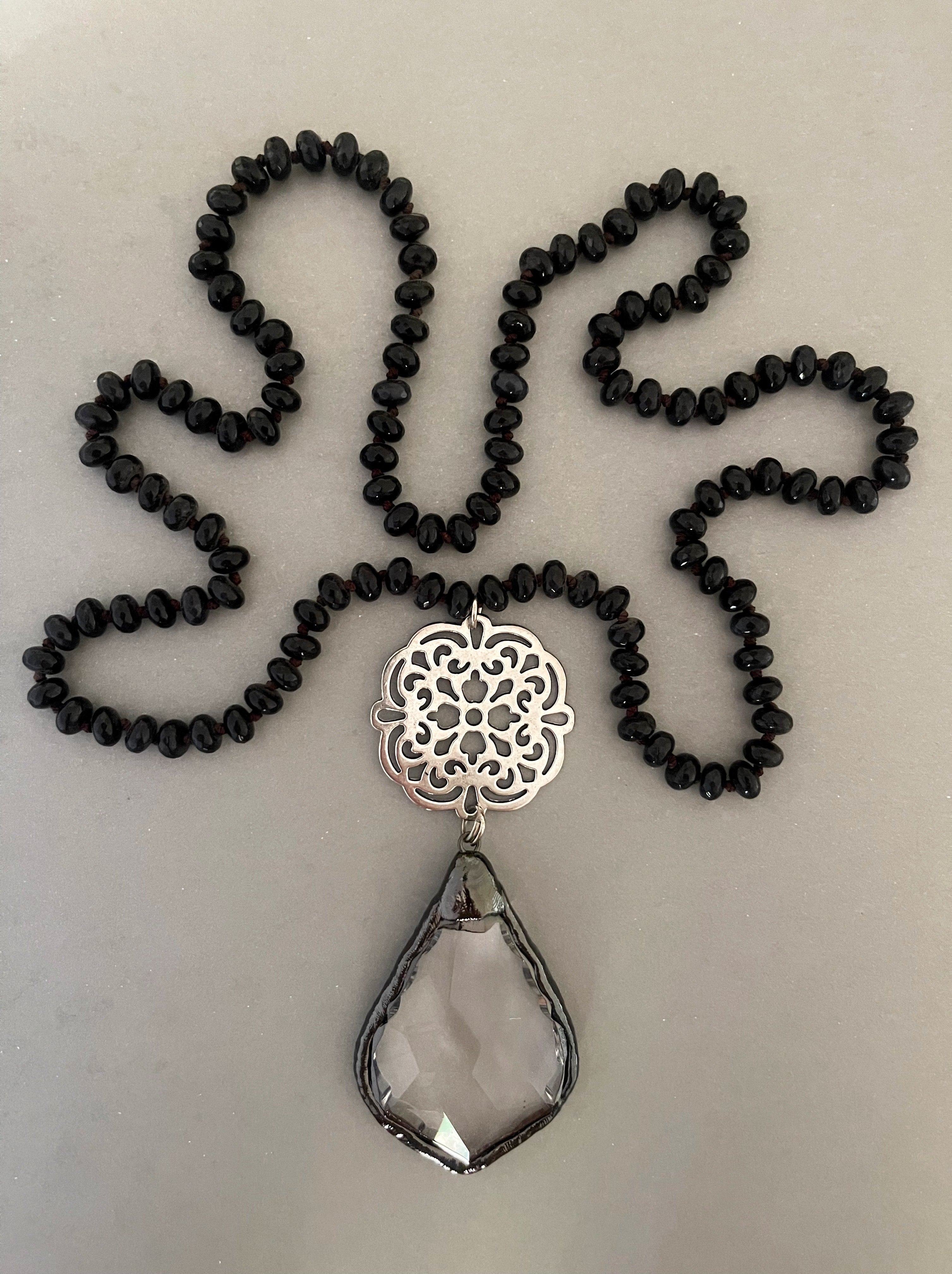 Collar Hippie Chic largo de elegantes piedras naturales negras abacos anudadas y colgante de cristal facetado y base plateada.