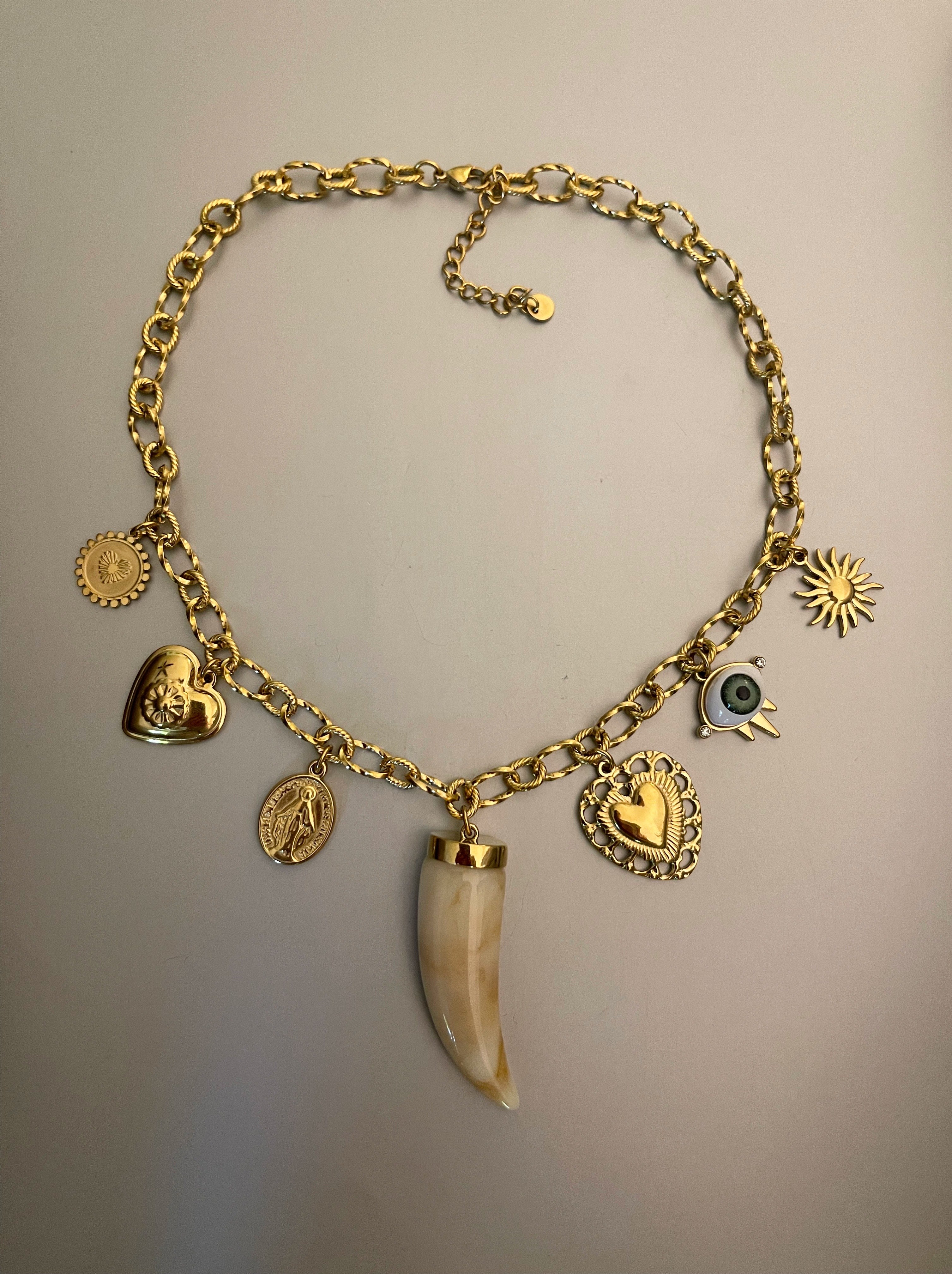 Collar Hippie Chic corto con cadena de acero inoxidable dorado y preciosos colgantes con un colmillo principal en acrilico en tonos beige.