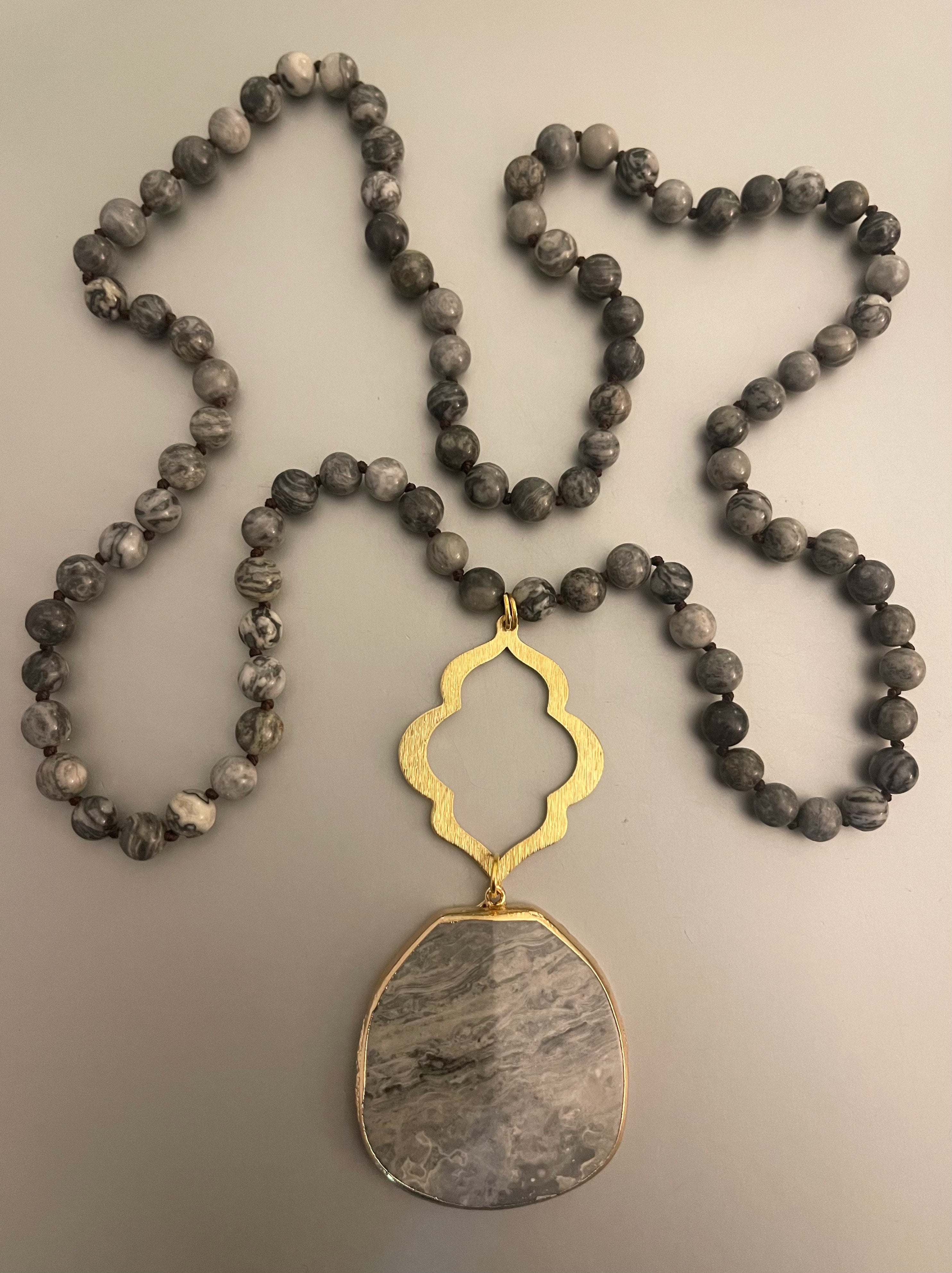 Collar Hippie Chic largo de elegantes piedras en tonos grises anudadas y conector dorado.