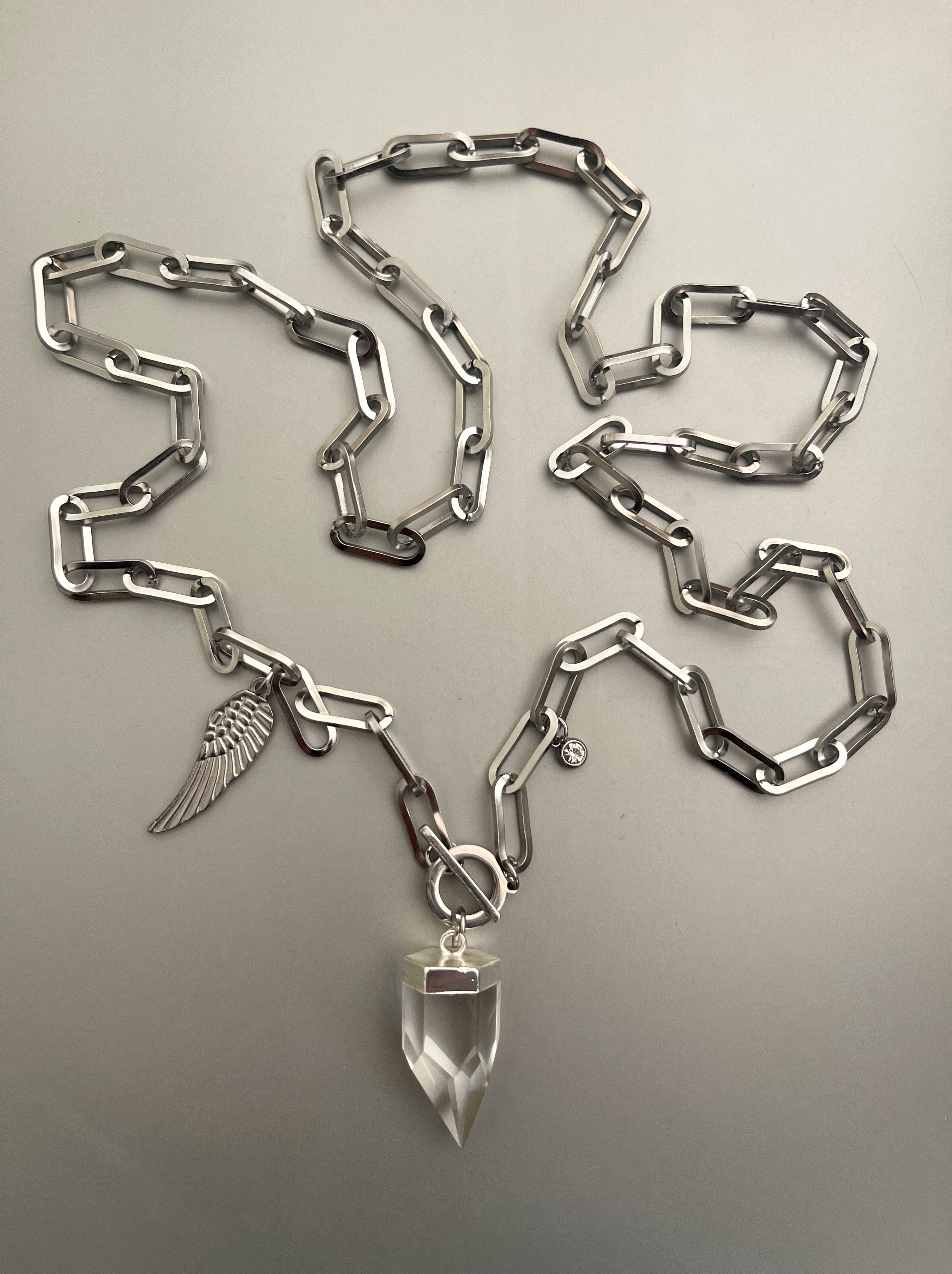 Collar Hippie Chic largo de acero inoxidable plateado, cierre OT y  precioso cuarzo facetado translúcido con colgante de ala y punto de luz.