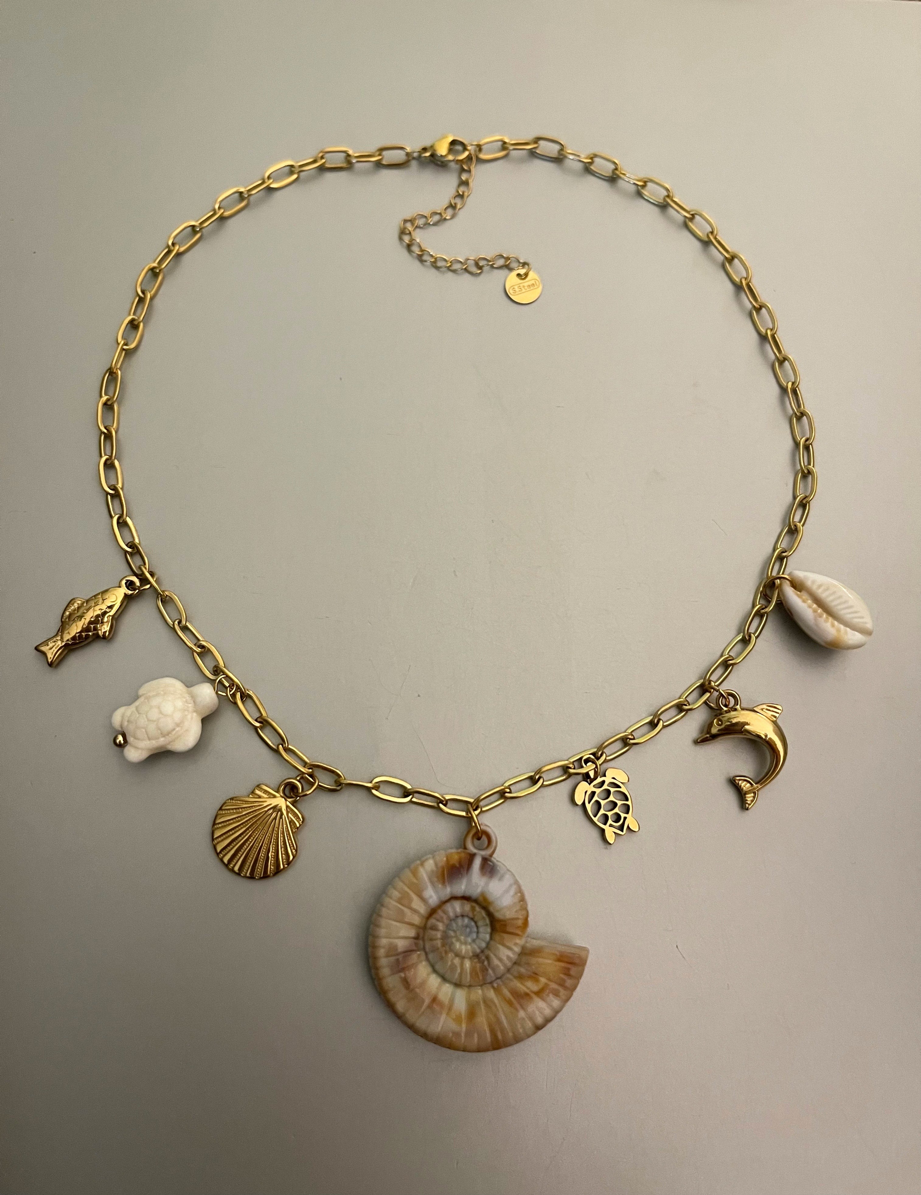 Collar Hippie Chic corto de cadena de acero inoxidable dorado y preciosos colgantes con motivos maritimos en acero y acrilico en tonos beige.